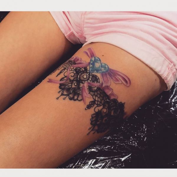 Jarretière avec motifs et ailes colorés et un cœur sur la jambe d'une fille