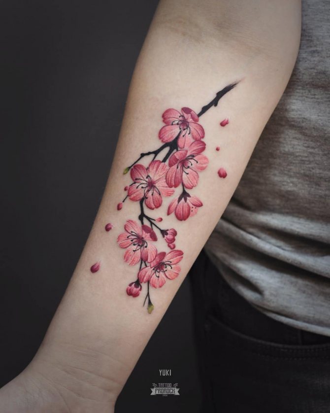 Tatouage réaliste d'une cerise sur le bras d'une fille