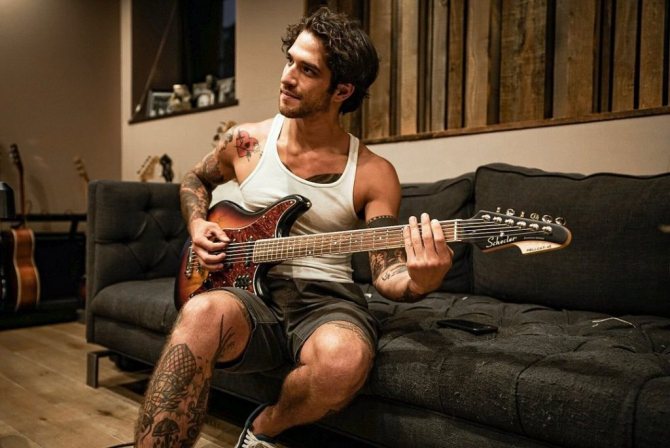 Tyler Posey se sienta en el sofá con una guitarra.