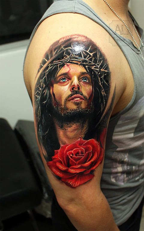 Tatuaje de Jesucristo con una corona de espinas y una rosa en el brazo