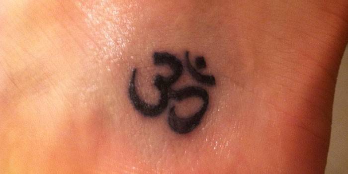 Tetoválás egy lány bokáján: Az Om szimbóluma