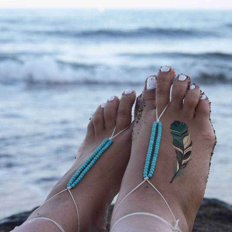 tatouage d'une plume sur sa jambe