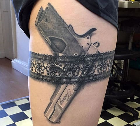 Garter belt gun tattoo on hip of a girl
