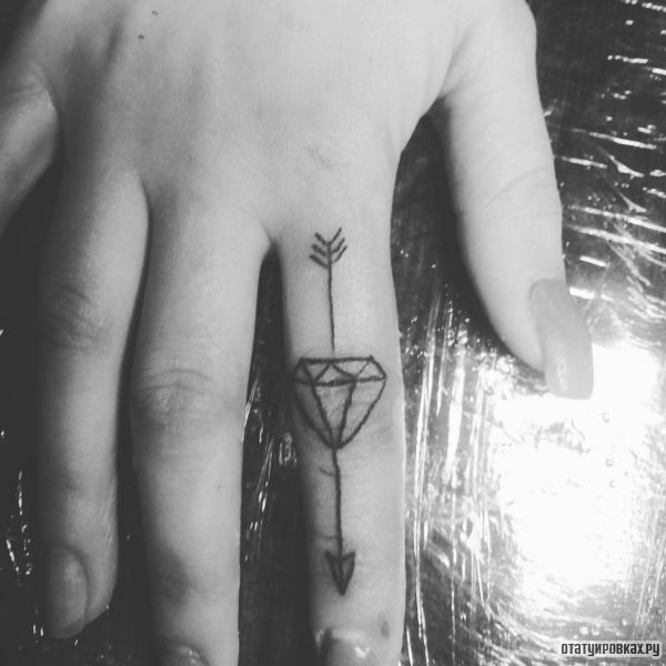 Tatouage d'une flèche avec un diamant sur le doigt