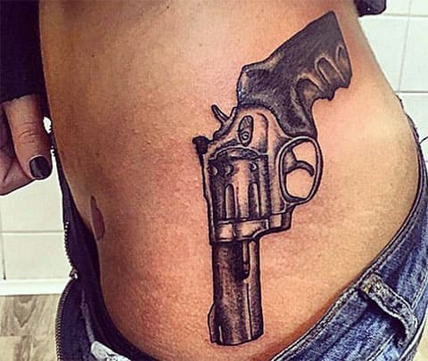 Tattoo with a gun on the side of a girl