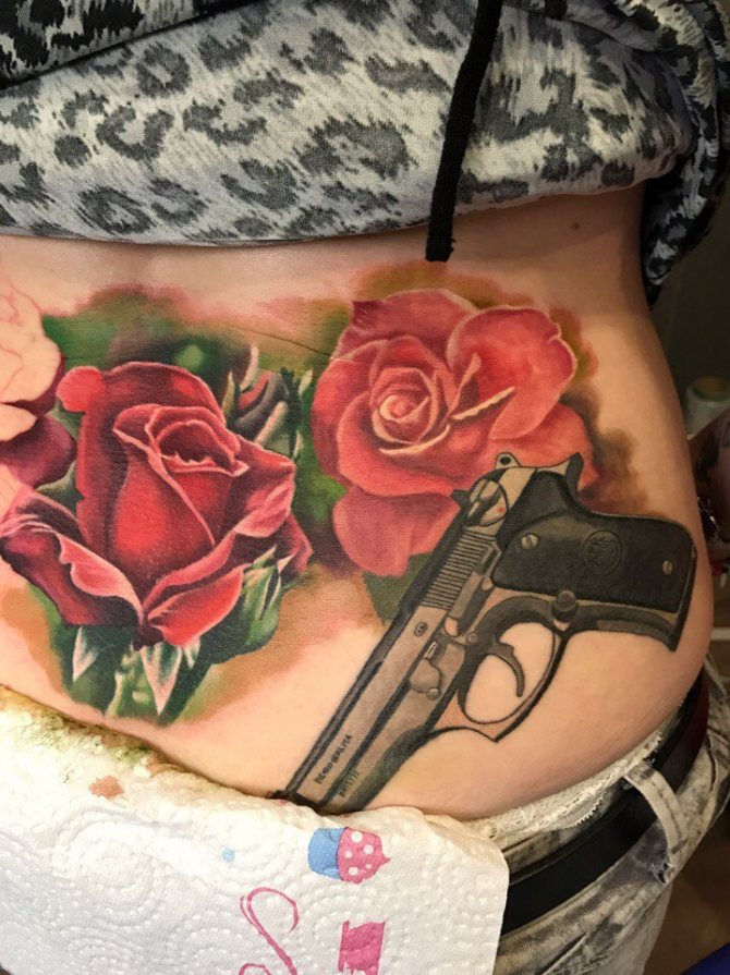 Une fille a un tatouage d'une rose avec un pistolet sur son corps.