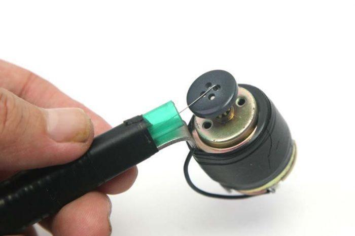 L'extrémité coudée est insérée dans le bouton